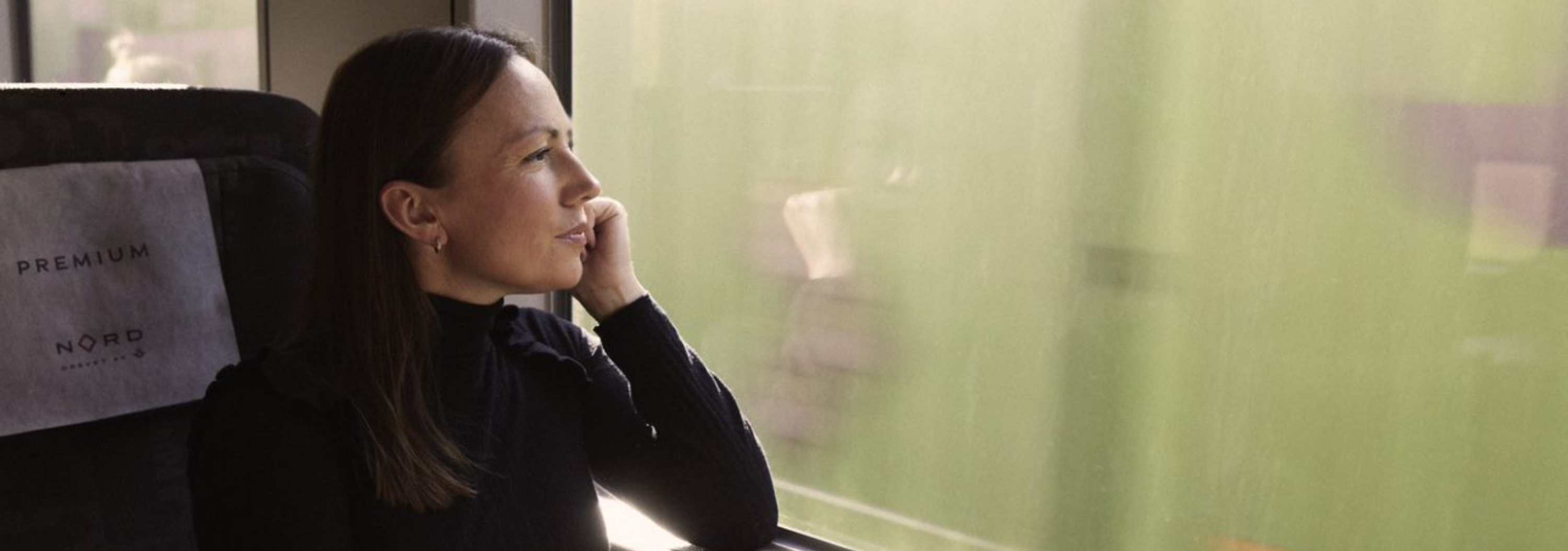 Kvinne sitter på toget og ser ut vinduet