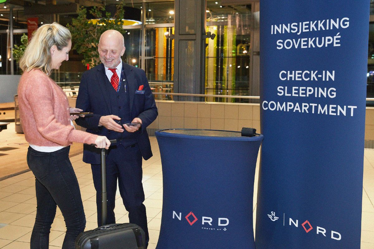 Dame sjekker inn på nattoget hos en SJ Norge ansatt
