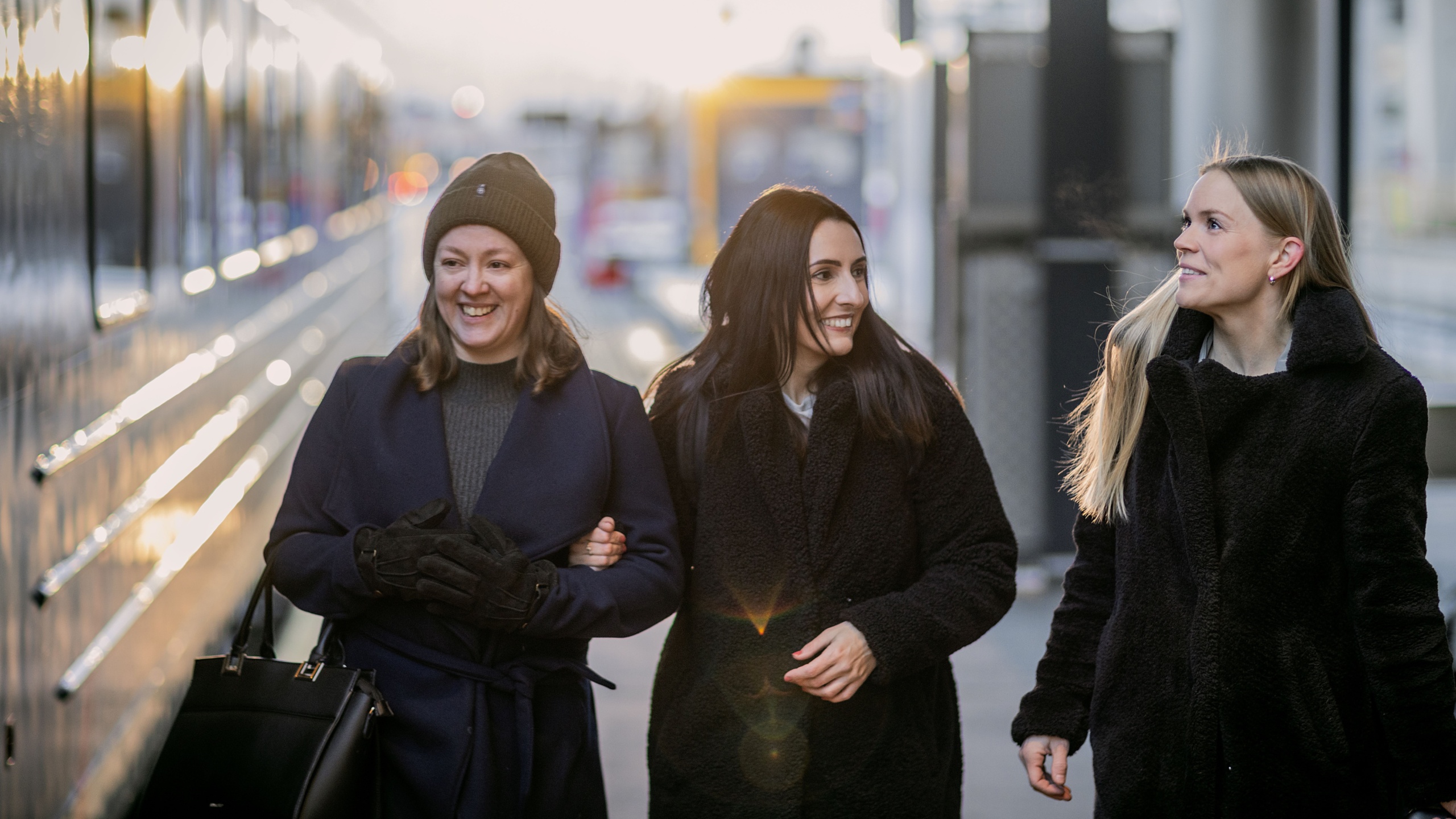 Three friends boarding the train at the train station.