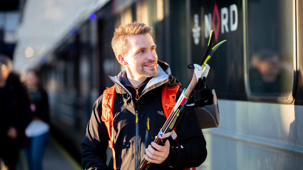 Passasjer bærer på skiene sine på vei til Ski-VM